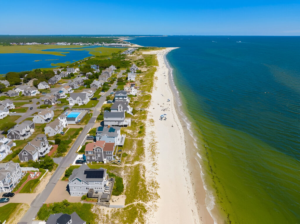 10 Of the Best East Coast Family Vacations and Destinations Sunny day at a Cape Cod beach with families playing in the sand and waves classic New England beach vacation